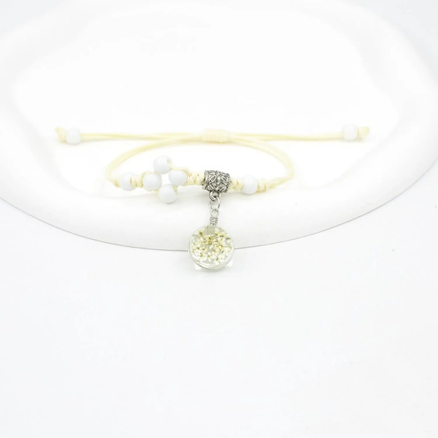 Glass bracelet with large colourful beads containing real dried flowers, on a white background.