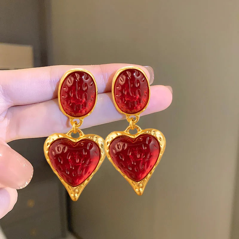 A pair of oval-shaped, pleated love heart stud earrings in alloy, shown in various colours.