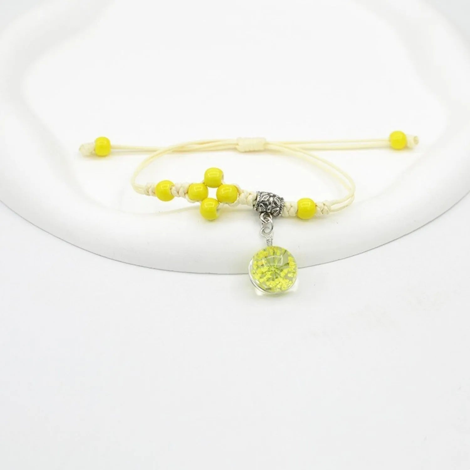 Glass bracelet with large colourful beads containing real dried flowers, on a white background.