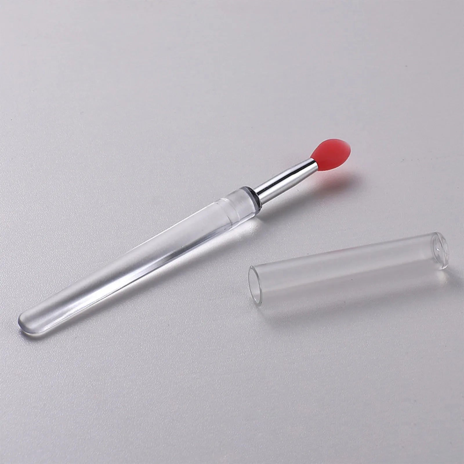 Set of eight colourful reusable silicone lip brushes with hygienic protective caps laid out.