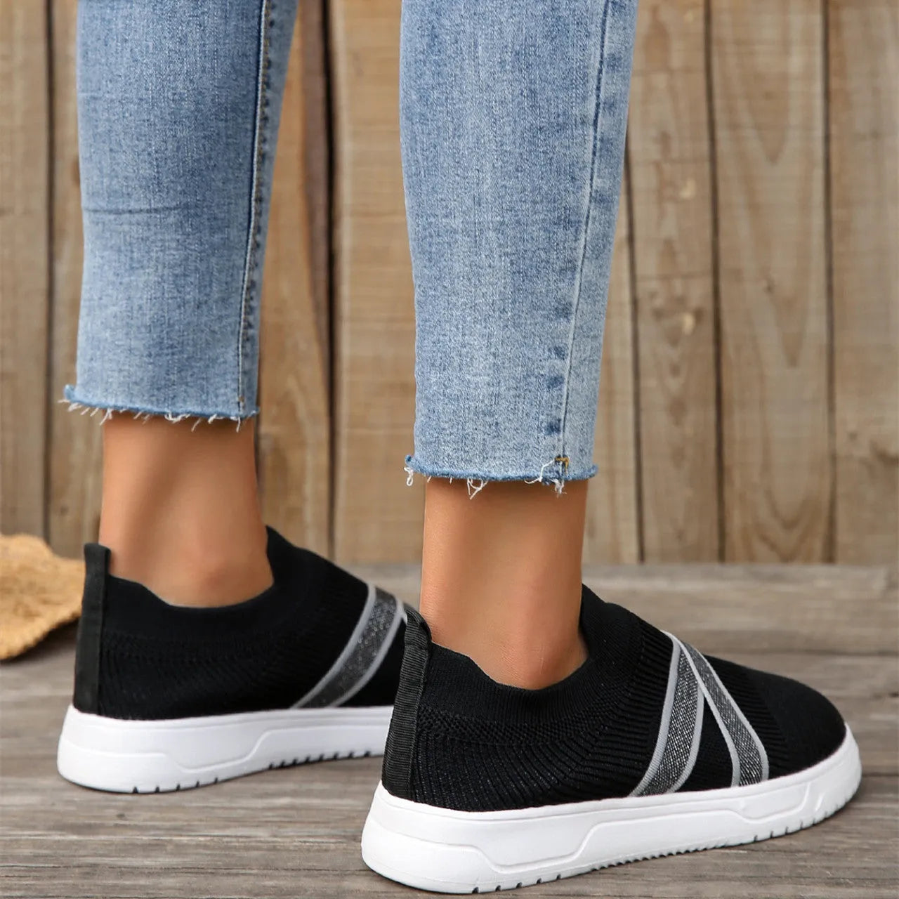Black women's flyknit mesh casual shoes with a flat rubber sole and a tassel detail on the upper.
