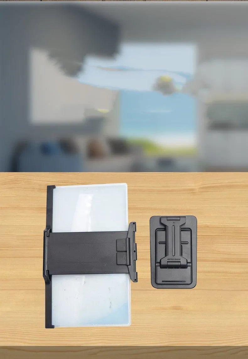 Black foldable mobile phone screen magnifier with detachable phone holder on a desk