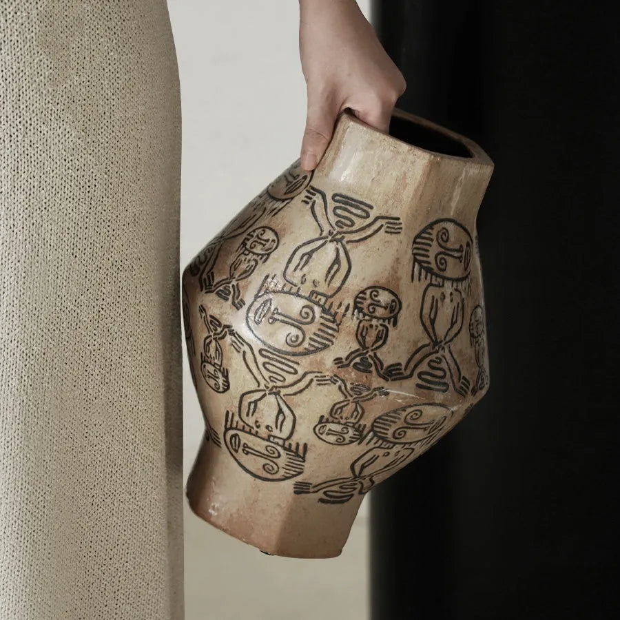 Hand-painted ceramic vase with carved tribal totem art in cylindrical shape.