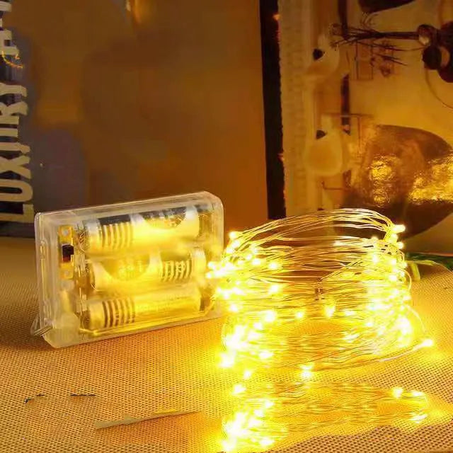 Copper wire battery-operated string lights wrapped around branch with multiple LED colours illuminated