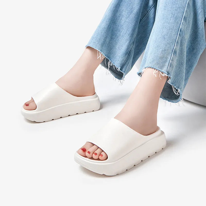 Women's beige thick soled EVA beach slippers with fish mouth design on a wooden floor