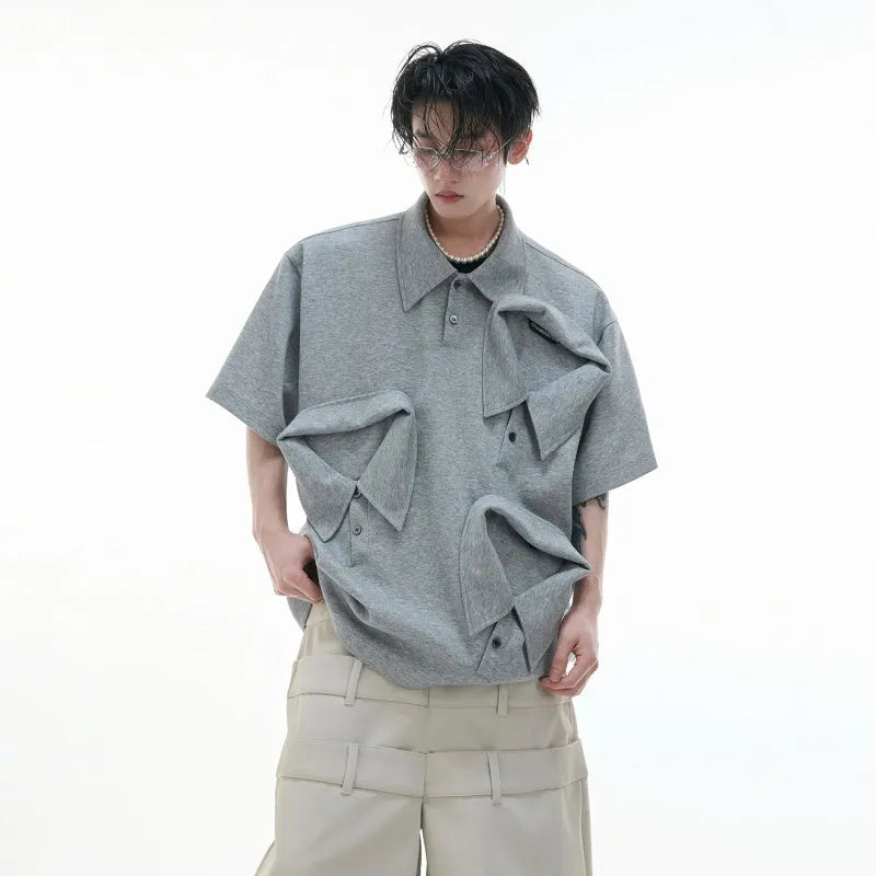 Man modelling a loose-fit black polo shirt with a deconstructed collar and a geometric pattern on the chest.