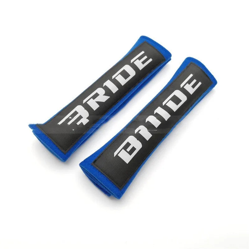 Pair of black cotton seat belt shoulder sleeves with embroidery, shown next to a car seat.