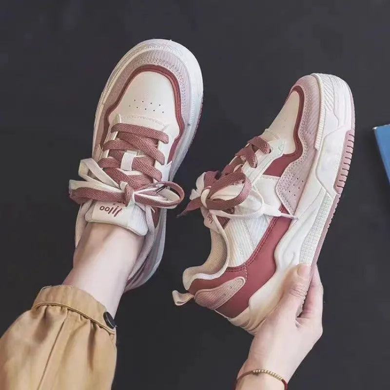 Pink and beige low-top sneakers with a rubber sole and imitation leather upper.