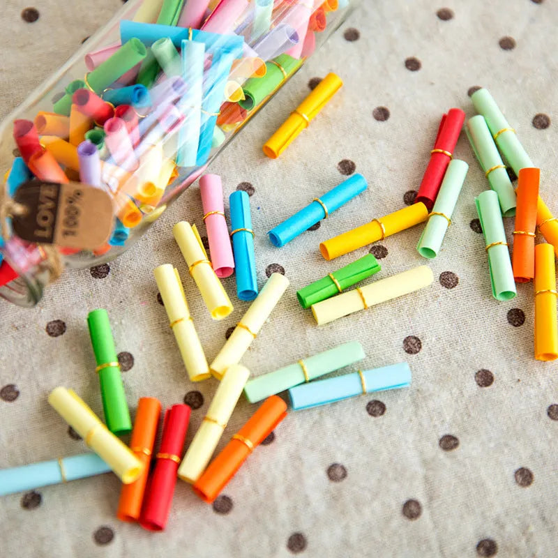 Assortment of colourful mini paper scrolls with metal eyelets in various sizes.