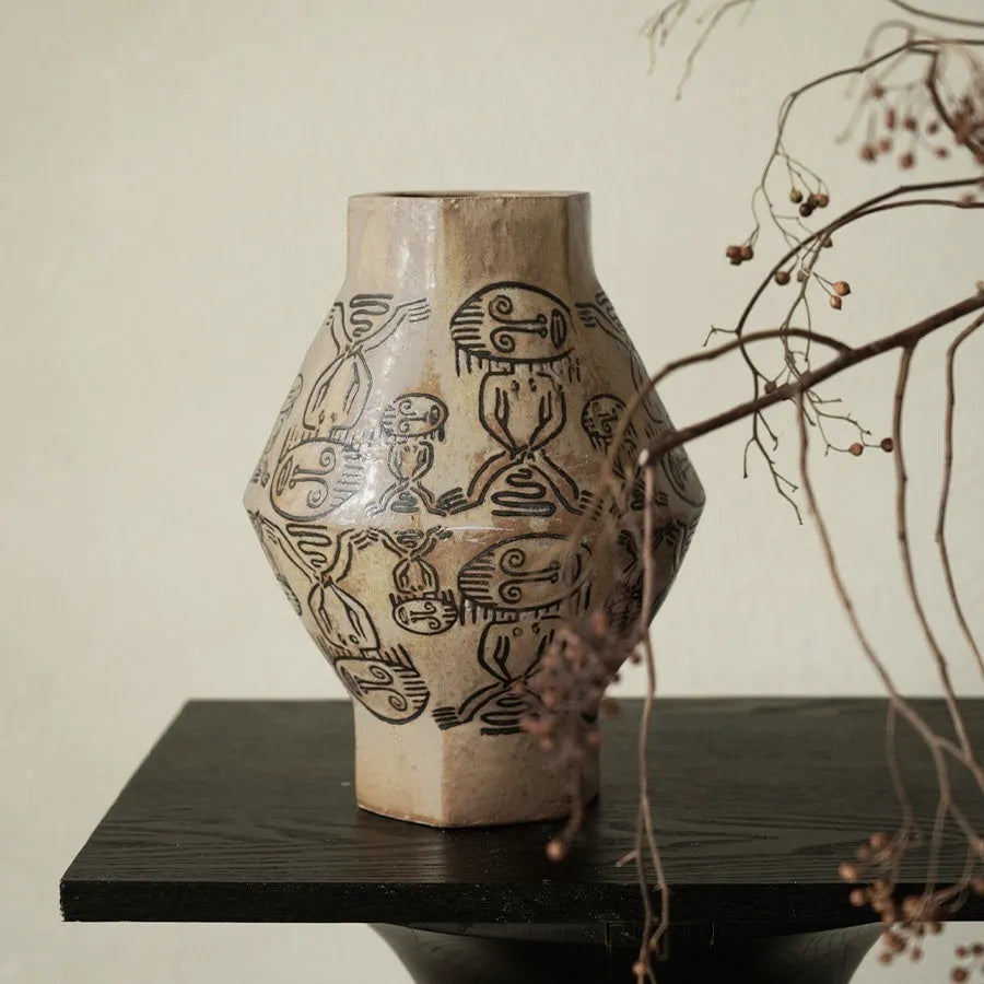 Hand-painted ceramic vase with carved tribal totem art in cylindrical shape.