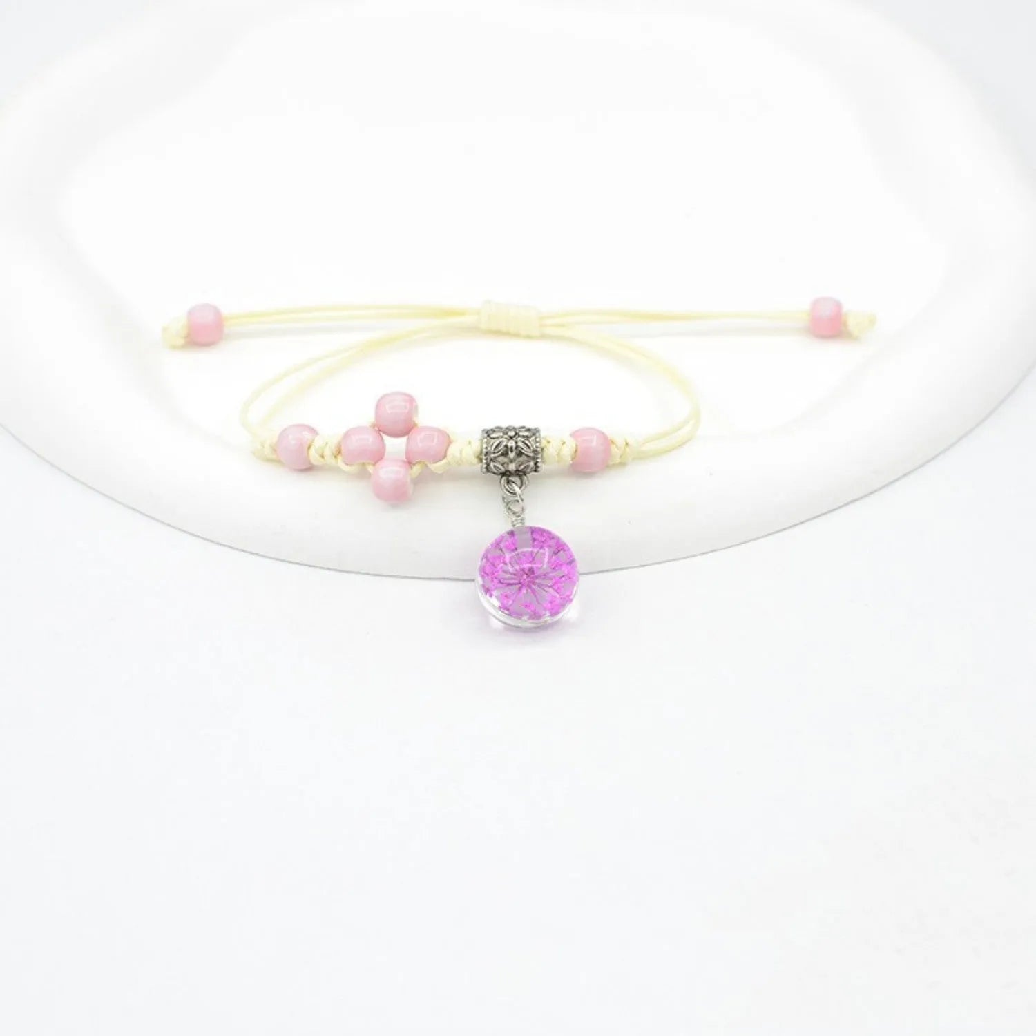 Glass bracelet with large colourful beads containing real dried flowers, on a white background.
