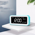 Blue rectangular LED alarm clock with atmosphere lighting on a wooden desk.
