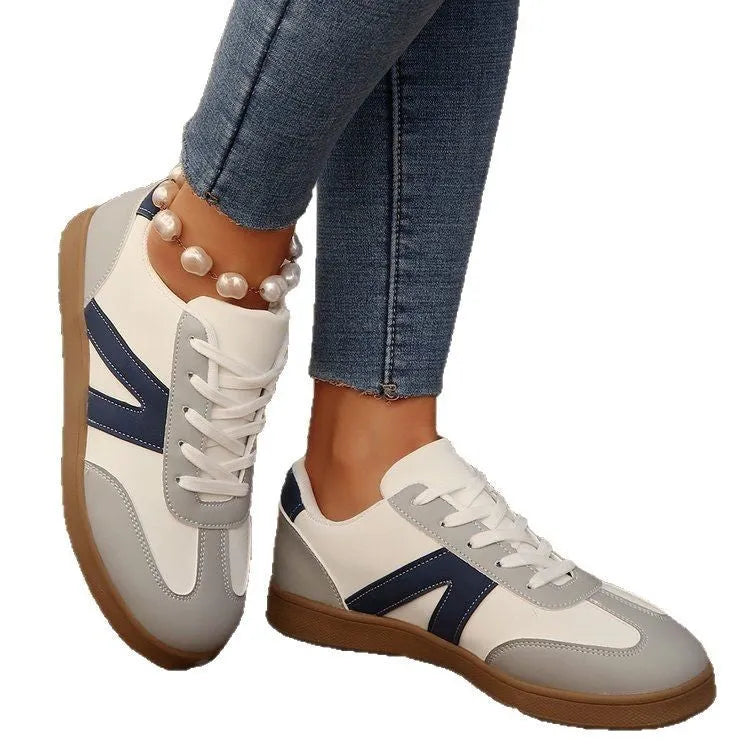 Blue women's low-top hiking shoes with flat rubber sole and lace-up front on artificial grass.
