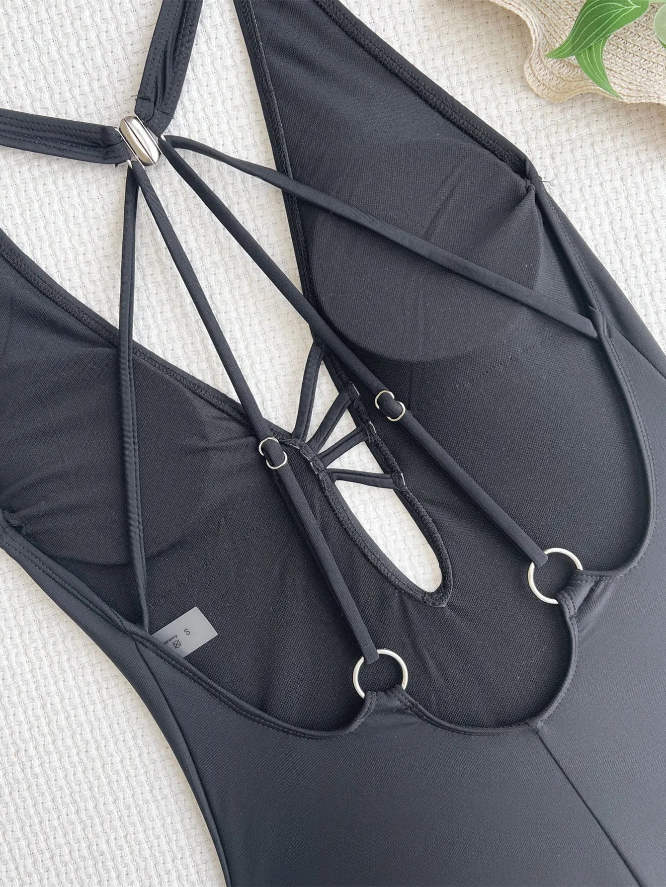 Black solid colour ladies nylon bikini swimsuit laid flat.