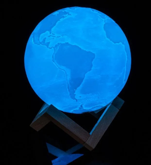 3D printed spherical moon lamp with textured surface on a wooden stand, showing white LED light.