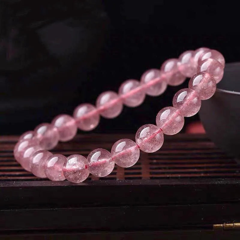 Women's bracelet with round, polished strawberry quartz crystal stones in natural pink tones.