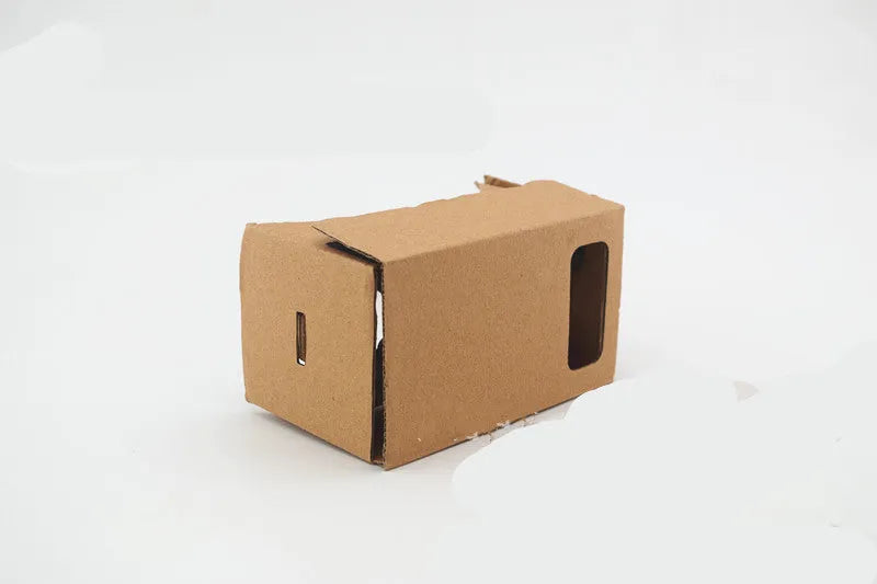 Pink and white cardboard VR glasses headset for smartphones, showing lenses, head strap, and magnetic button.