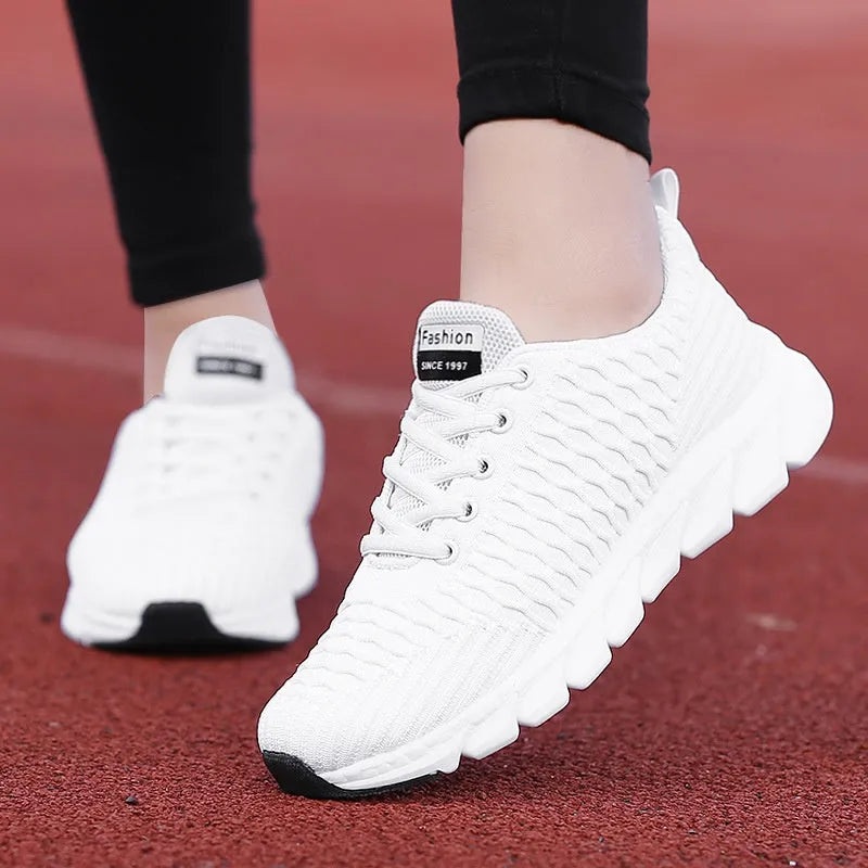 Women's running shoes in black, pink, or white with a woven fly knit upper and textured outsole.
