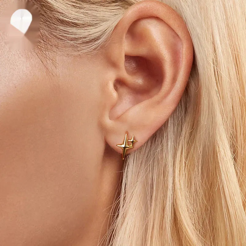 Minimalist oxidised sterling silver star ear clip with XINGX detail on a white background.