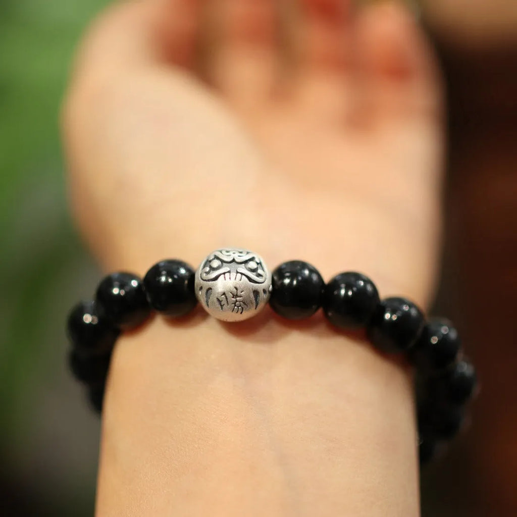 Close-up of a bracelet with large round black agate beads and a sterling silver clasp on a wrist.