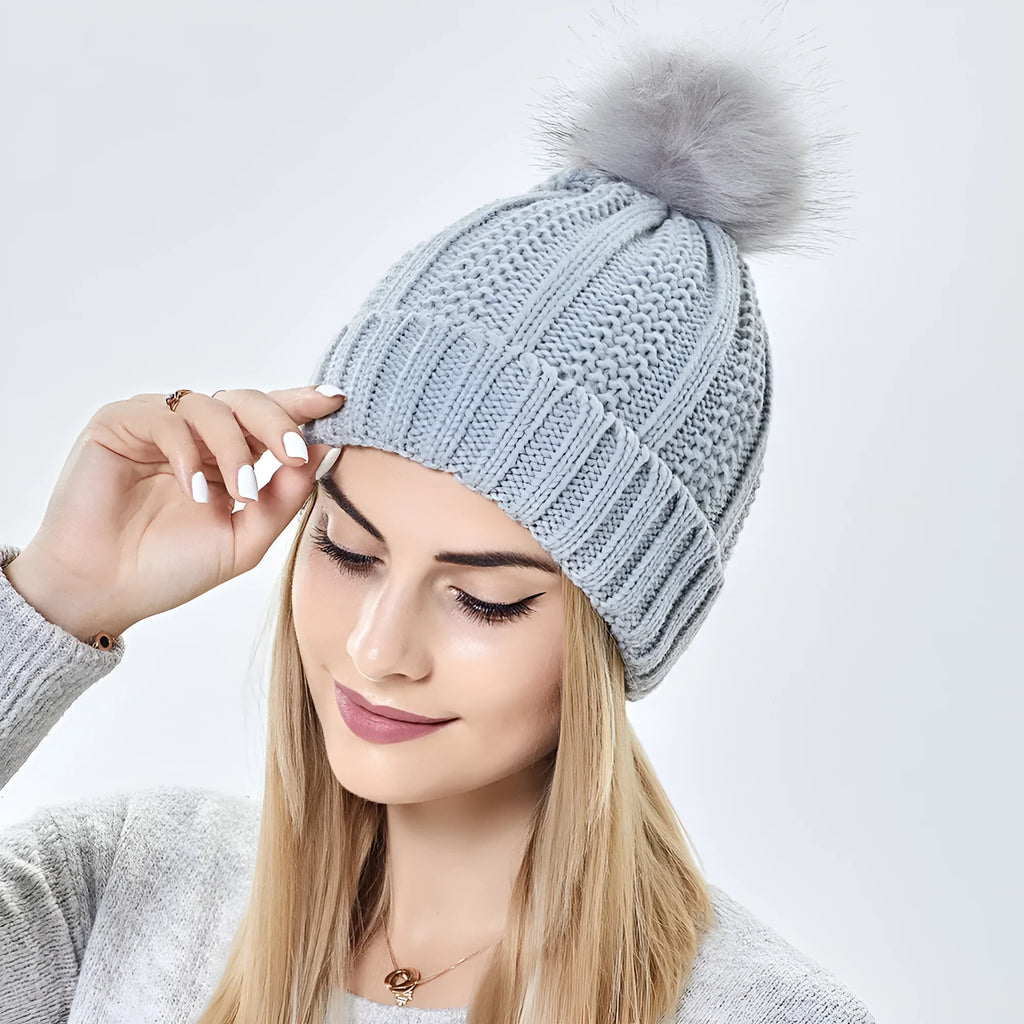 Women's black wool beanie hat with a faux fur pom pom and satin lining on a white background