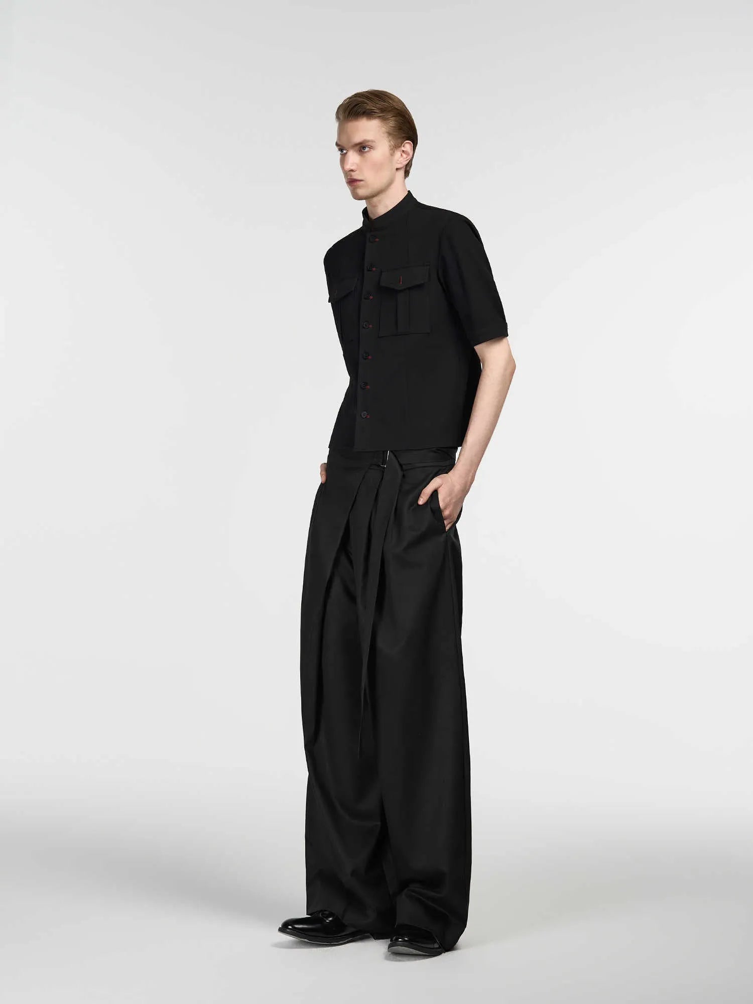Black straight-leg trousers with a single front pleat and adjustable waistband, laid flat.
