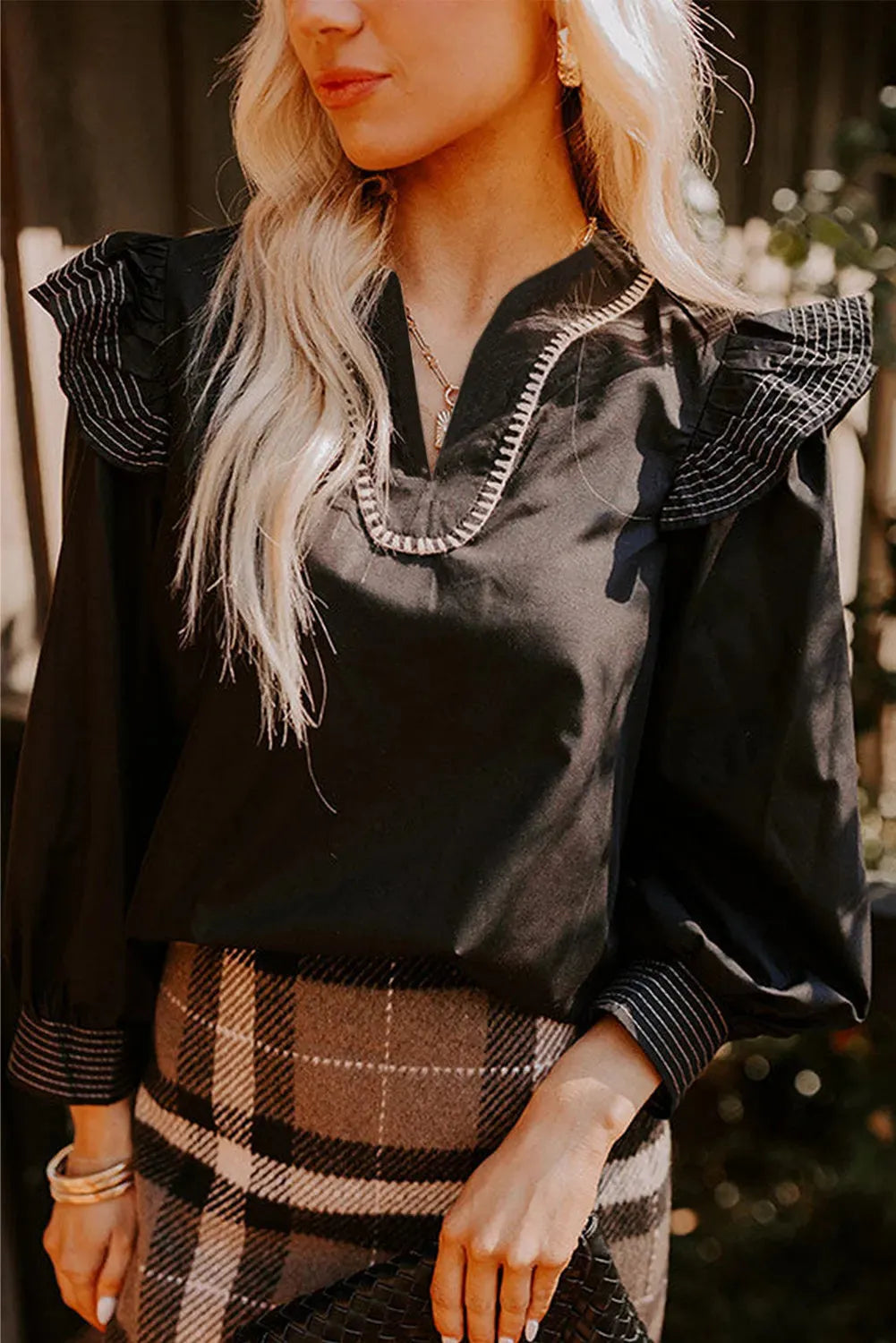 Black women's V-neck blouse with contrast stitching and long ruffle sleeves