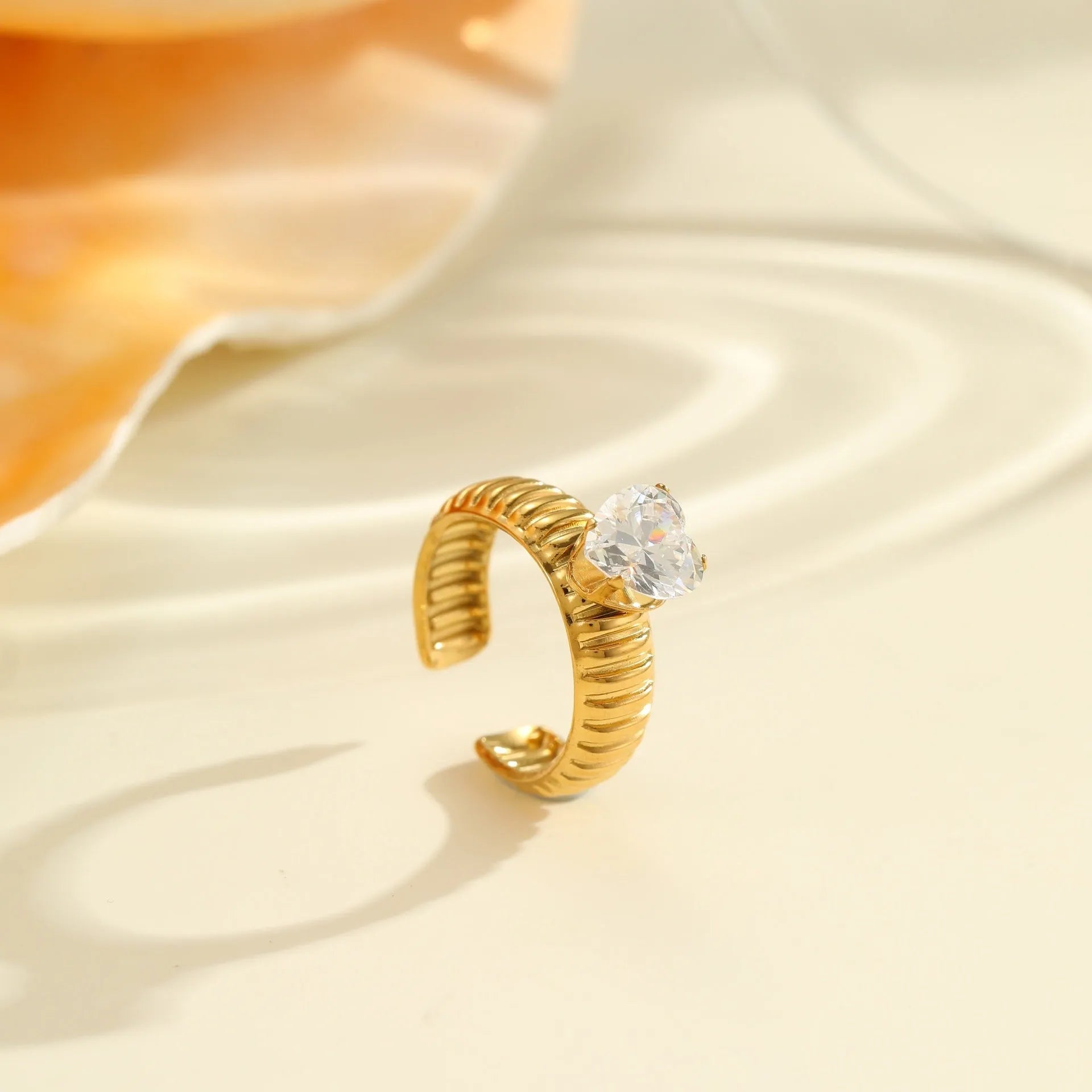 Gold-plated geometric stainless steel ring with inlaid zircon stones on a white background.