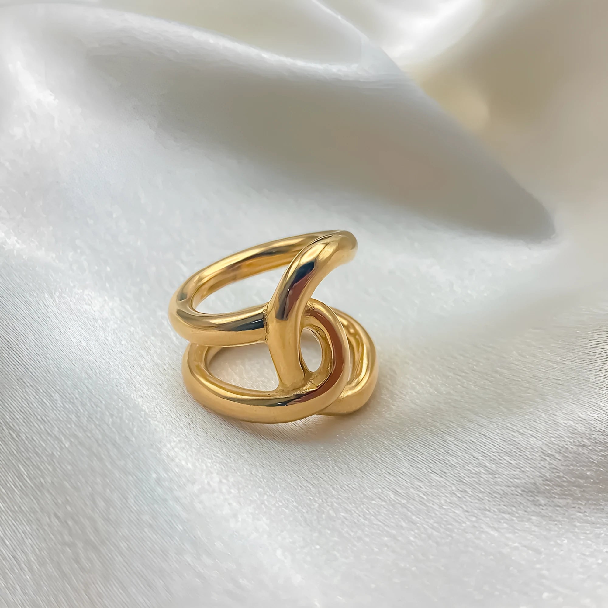 A geometric knotted adjustable ring for women in stainless steel, shown in gold and steel colour finishes.