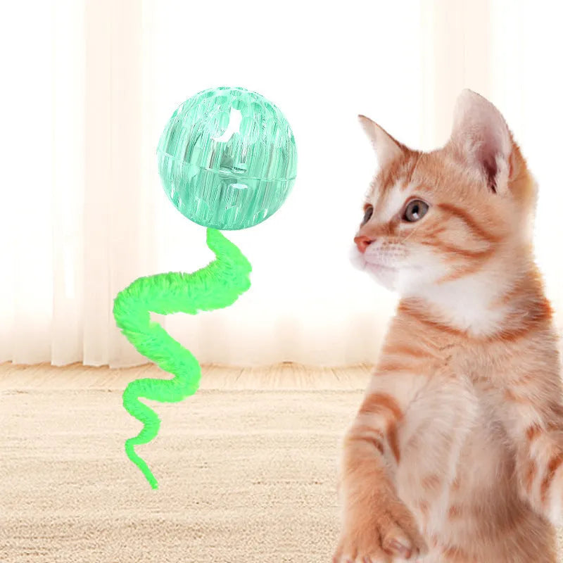 Interactive cat toy with purple bouncy ball and plush tail on wooden floor