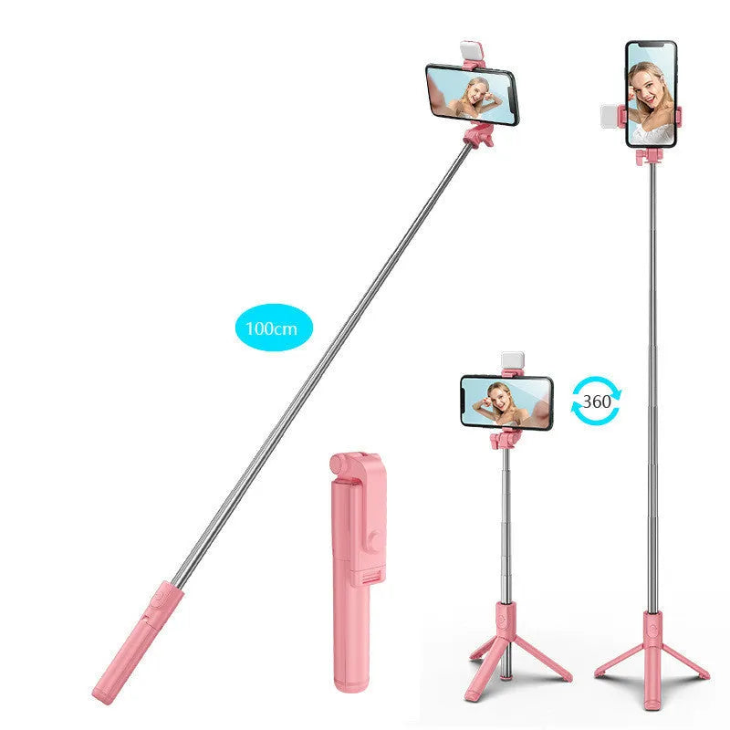 Black Bluetooth selfie stick with extended tripod legs, fill light, and a phone mounted in the 360-degree rotatable holder.