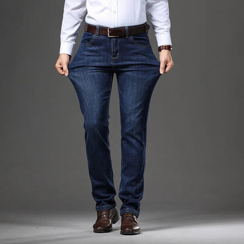 Man wearing black loose fit straight leg stretch denim jeans, showing mid waist and zip fly.