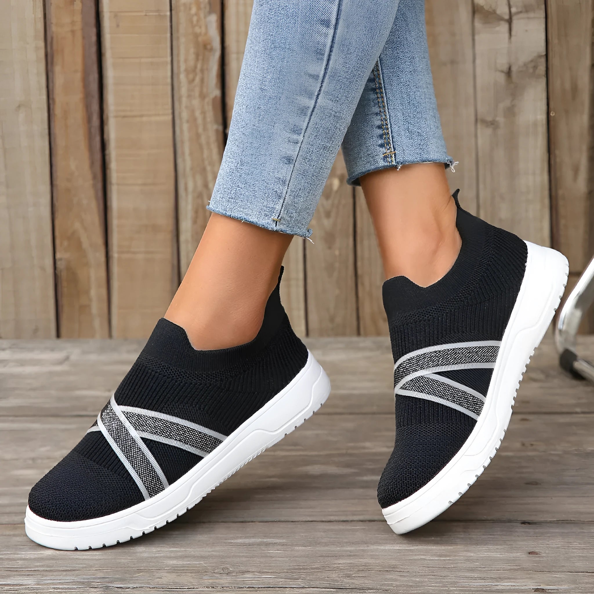 Black women's flyknit mesh casual shoes with a flat rubber sole and a tassel detail on the upper.