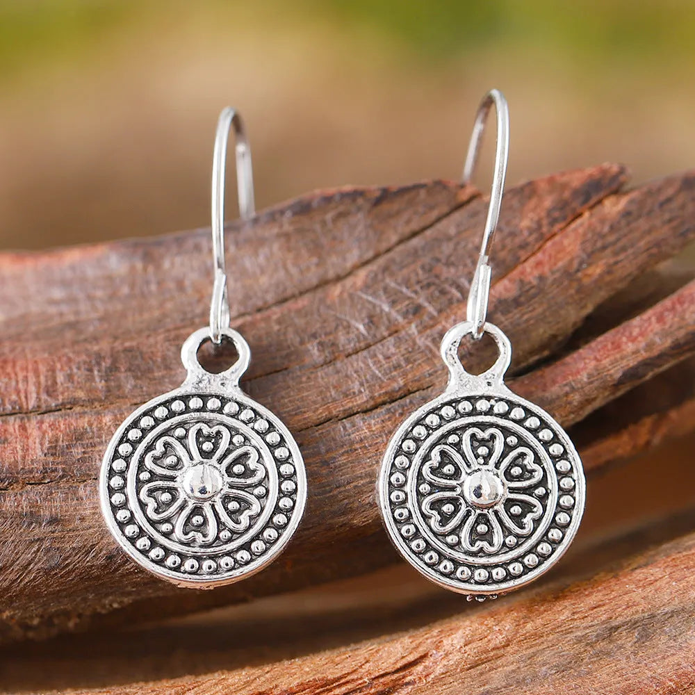A pair of bohemian retro geometric earrings with a distressed finish and round elements.
