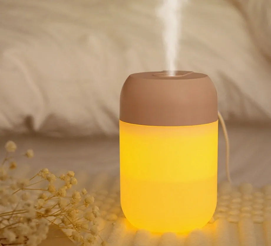 Small white cylindrical USB-powered mini humidifier on a wooden desk.