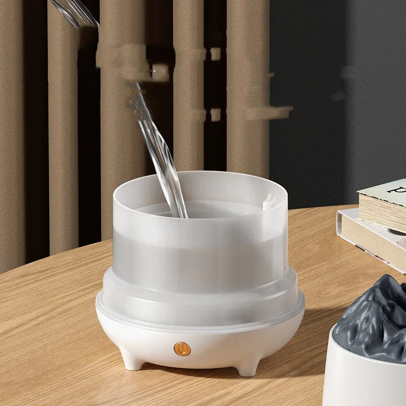 Black and white volcano-shaped ultrasonic humidifier with USB cable on a desk.