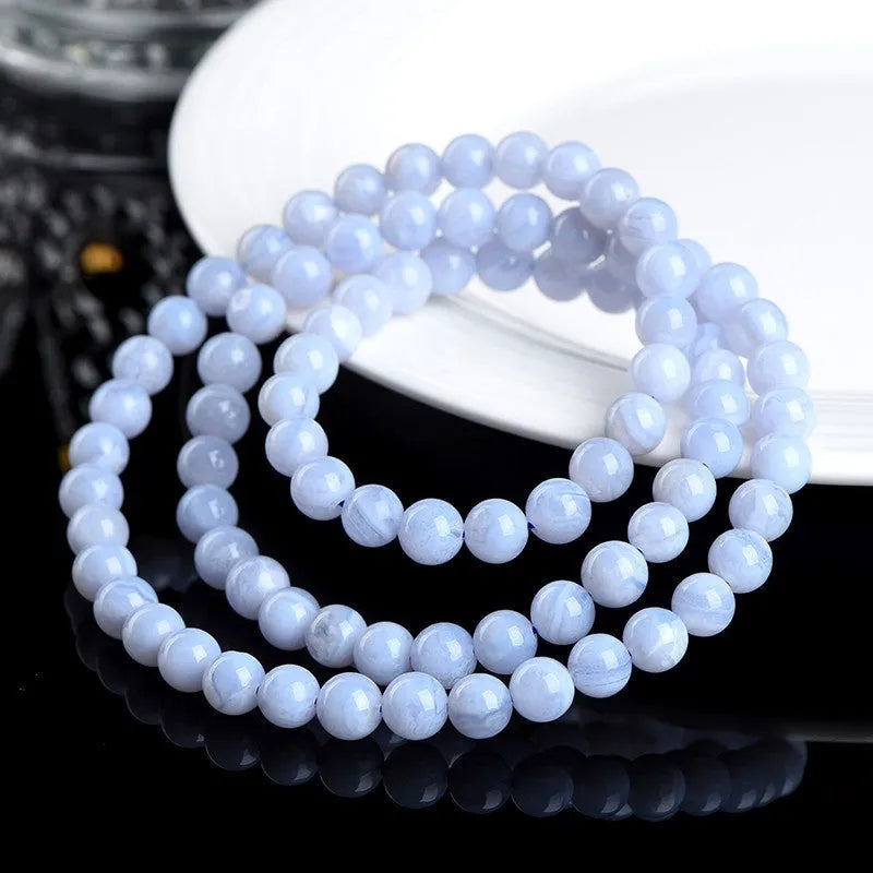 Blue agate bracelet with scattered beads pattern and a Ruyi charm on a white background.