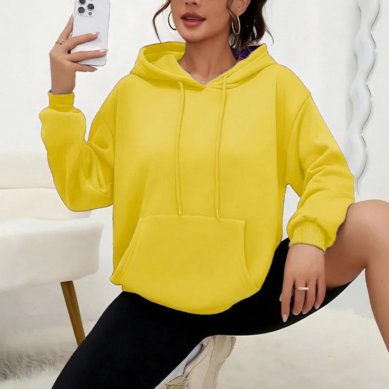 Woman wearing a loose grey drawstring waist sweatshirt with front pockets and long sleeves.