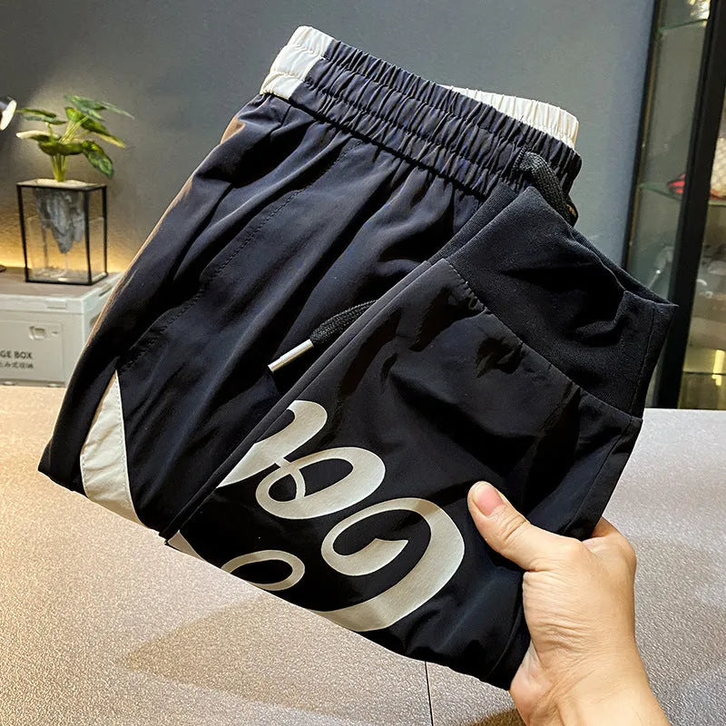 Men's solid black cotton cropped trousers with elasticated ankle band cuffs laid flat.