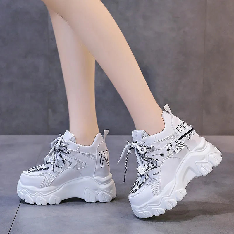 Women's white and black mesh platform tennis shoes with cross strap and thick rubber sole.