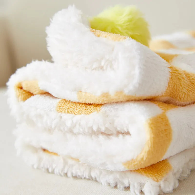Plush cotton fleece pet blanket with plaid pattern and fur balls in green colour on couch