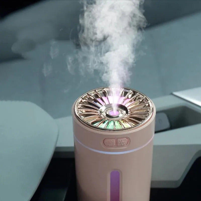 Black portable ultrasonic humidifier with colourful LED lights, shown next to a USB cable on a desktop.