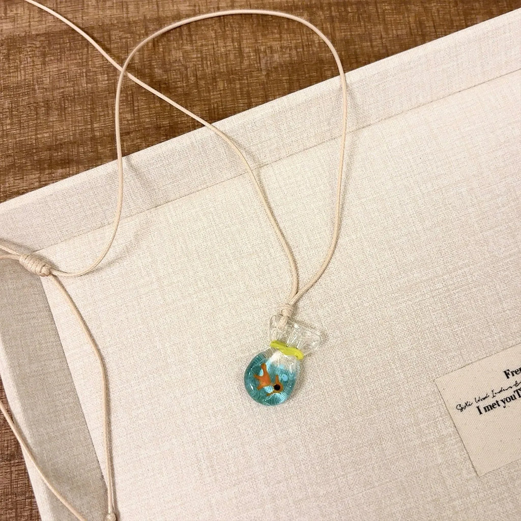 Women's necklace with coloured glaze joker charm on cotton linen chain in small fish lucky bag colour