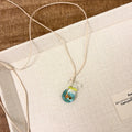 Women's necklace with coloured glaze joker charm on cotton linen chain in small fish lucky bag colour