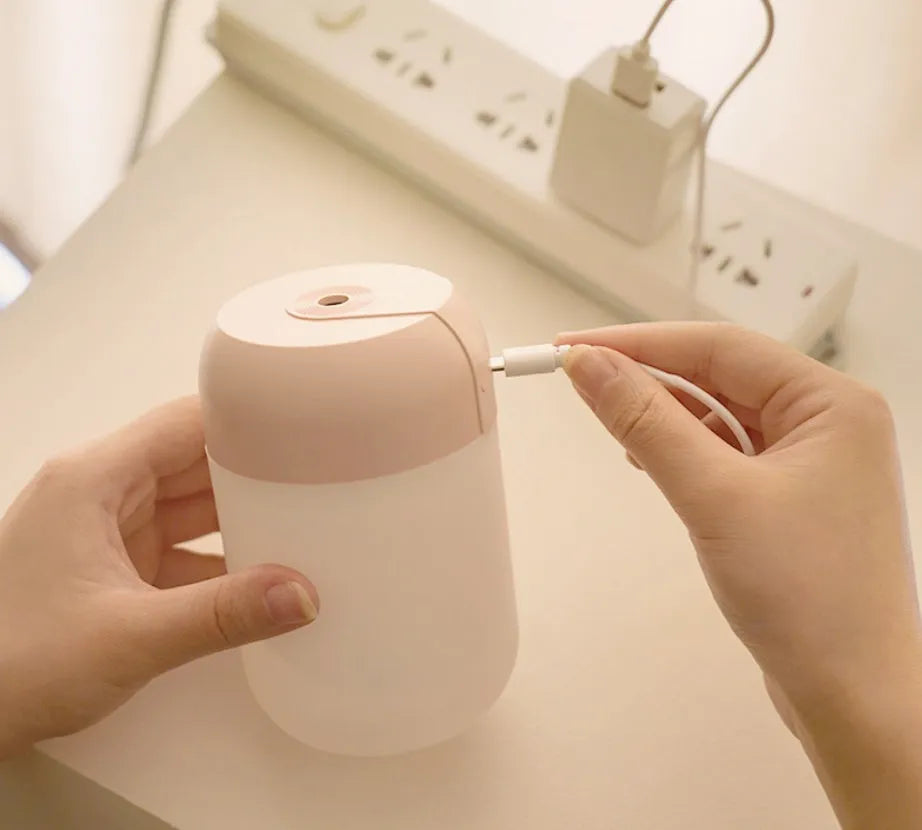 Small white cylindrical USB-powered mini humidifier on a wooden desk.