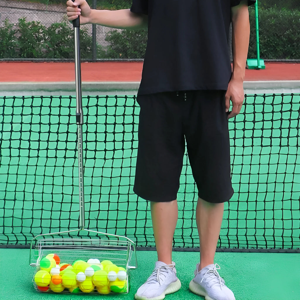 Stainless steel roller tennis ball picker with adjustable handle on a court.