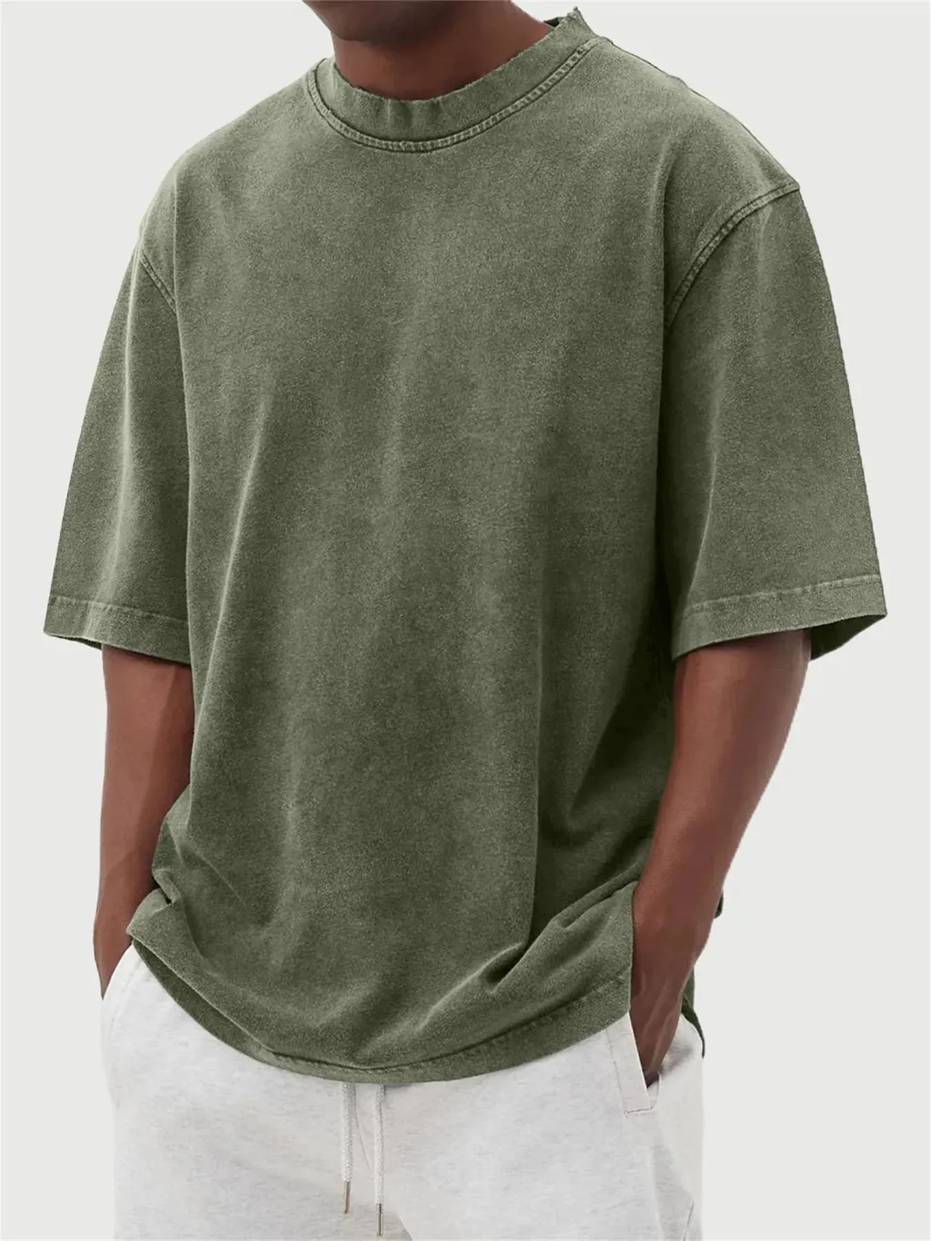Man wearing a loose-fit, stone-washed distressed pullover T-shirt in a solid colour.