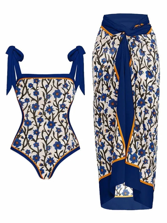 Women's floral print two-piece swimsuit with a blue chiffon skirt laid flat.