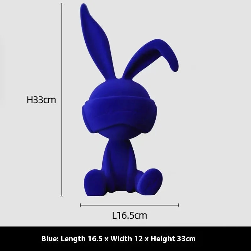 Green resin blindfold rabbit table ornament on a wooden surface.