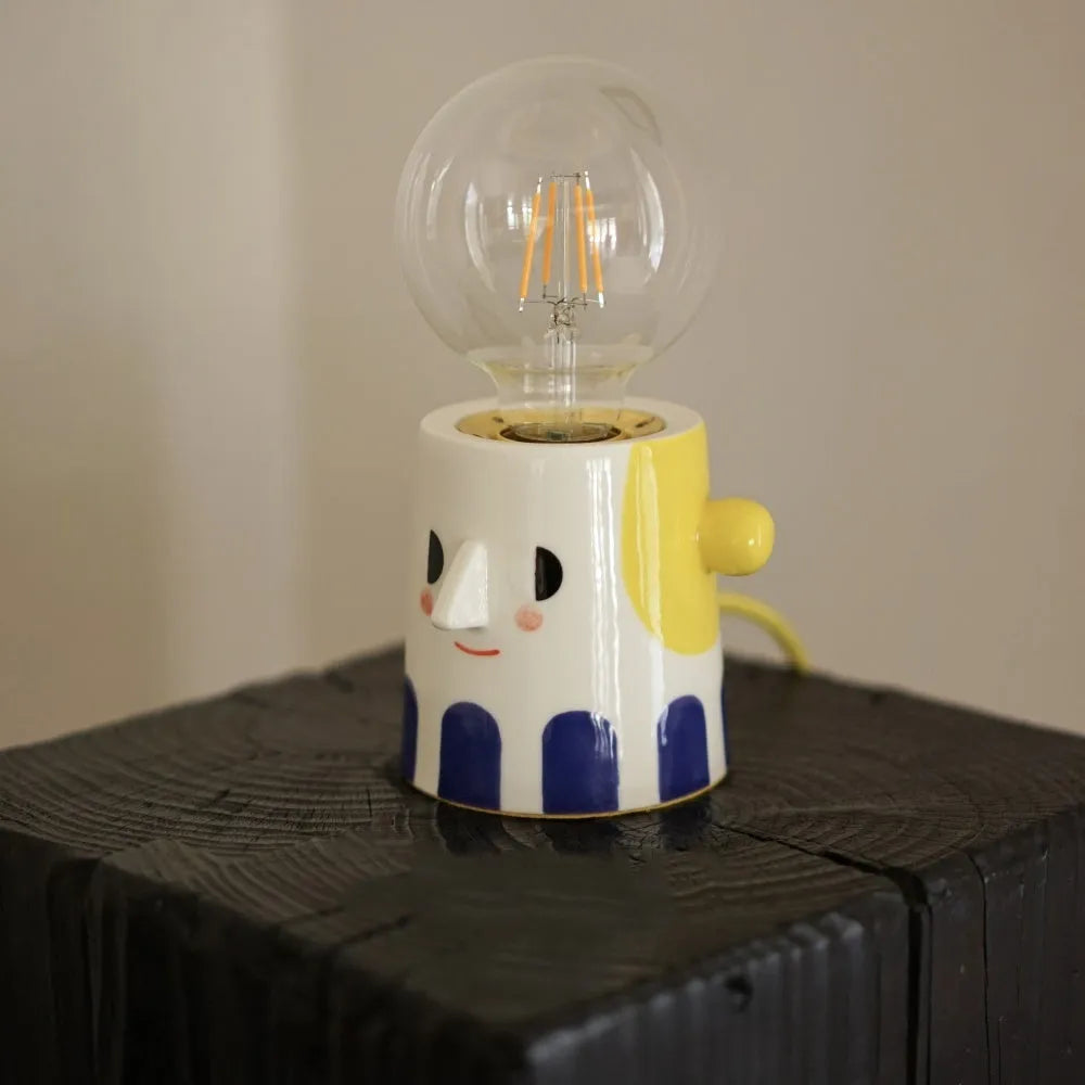 Handmade ceramic table lamp with a spherical ball headlight design on a bedside table.